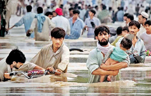A man wades through waist deep waters with his child while escaping floods in Risalpur in Pakistan's Northwest Frontier Province